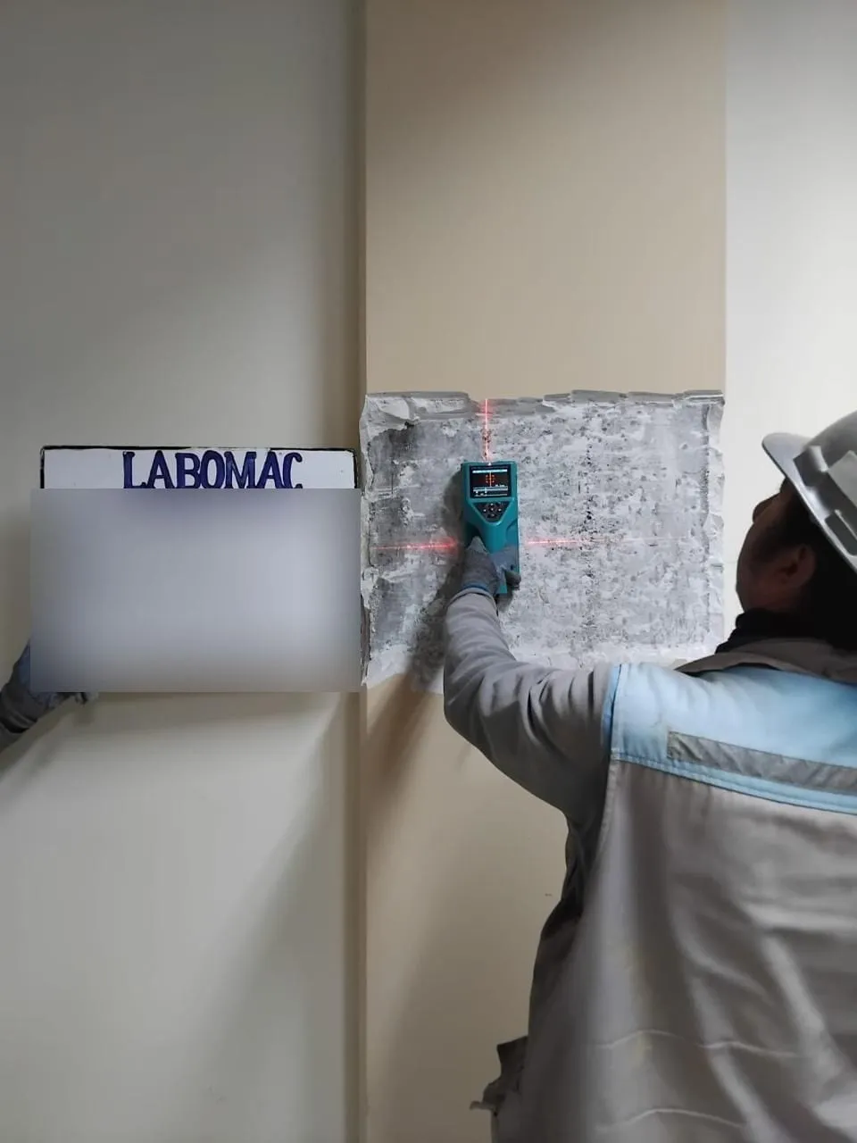 Técnico con casco usando un pachómetro sobre una columna de hormigón.